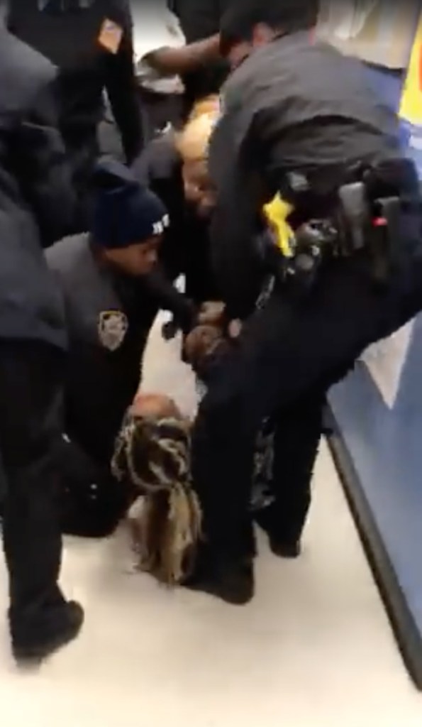 Police pull Jazmine Headley's toddler from her Monday as she sits on the floor waiting for service, in this still image from a video of the chaotic scene.