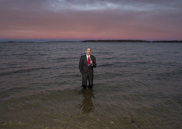 Wearing a business suit, swim goggles and holding a snorkel, Jason Wentworth stands in the water of Casco Bay off East End Beach recently. In the video on his GoFundMe page, Wentworth, who aspires to stand-up comedy focusing on climate change, swims out of the bay and walks up onto East End Beach in this get-up.