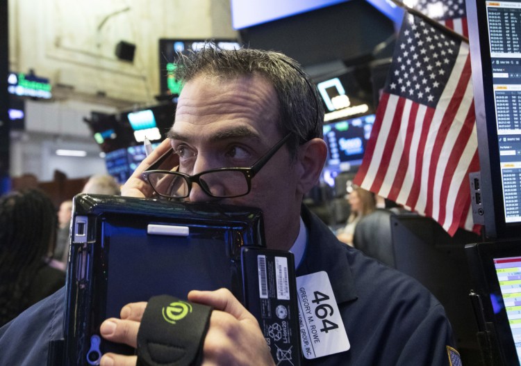 Trader Gregory Rowe works at the New York Stock Exchange on Dec. 12 in New York. Stocks suffered losses Monday.