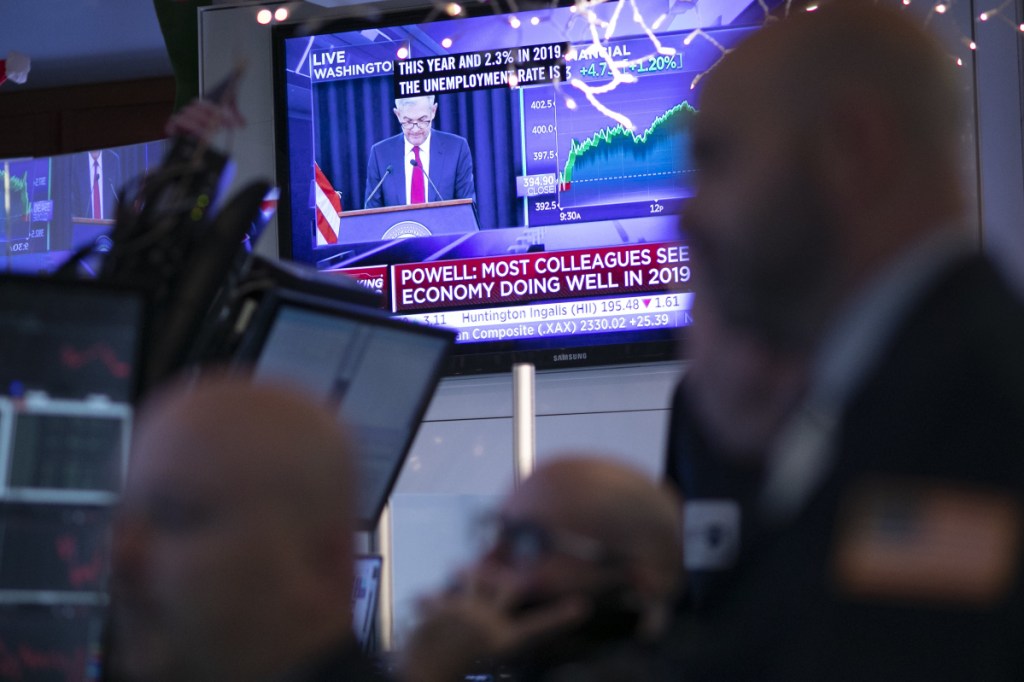 Traders at the New York Stock Exchange listen as Federal Reserve Chair Jerome Powell is seen on a video screen giving a news conference from Washington after the Fed announced a rate increase on Wednesday.