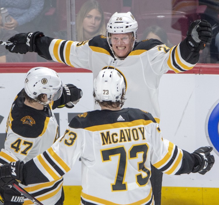 Boston Bruins centre Colby Cave, top, celebrates with teammates Torey Krug, left, and Charlie McAvoy after scoring his first NHL goal on Monday – the Bruins'  second goal in a 4-0 victory over the Canadiens in Montreal.