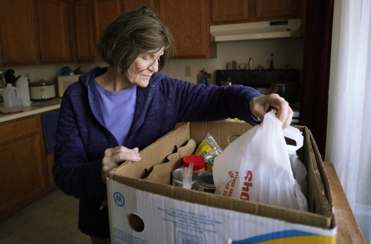 Nancy Cardoza, 67, looks through a box of food delivered to her by Freeport Community Services. A volunteer worries that she is merely helping to take the pressure off a larger problem.
