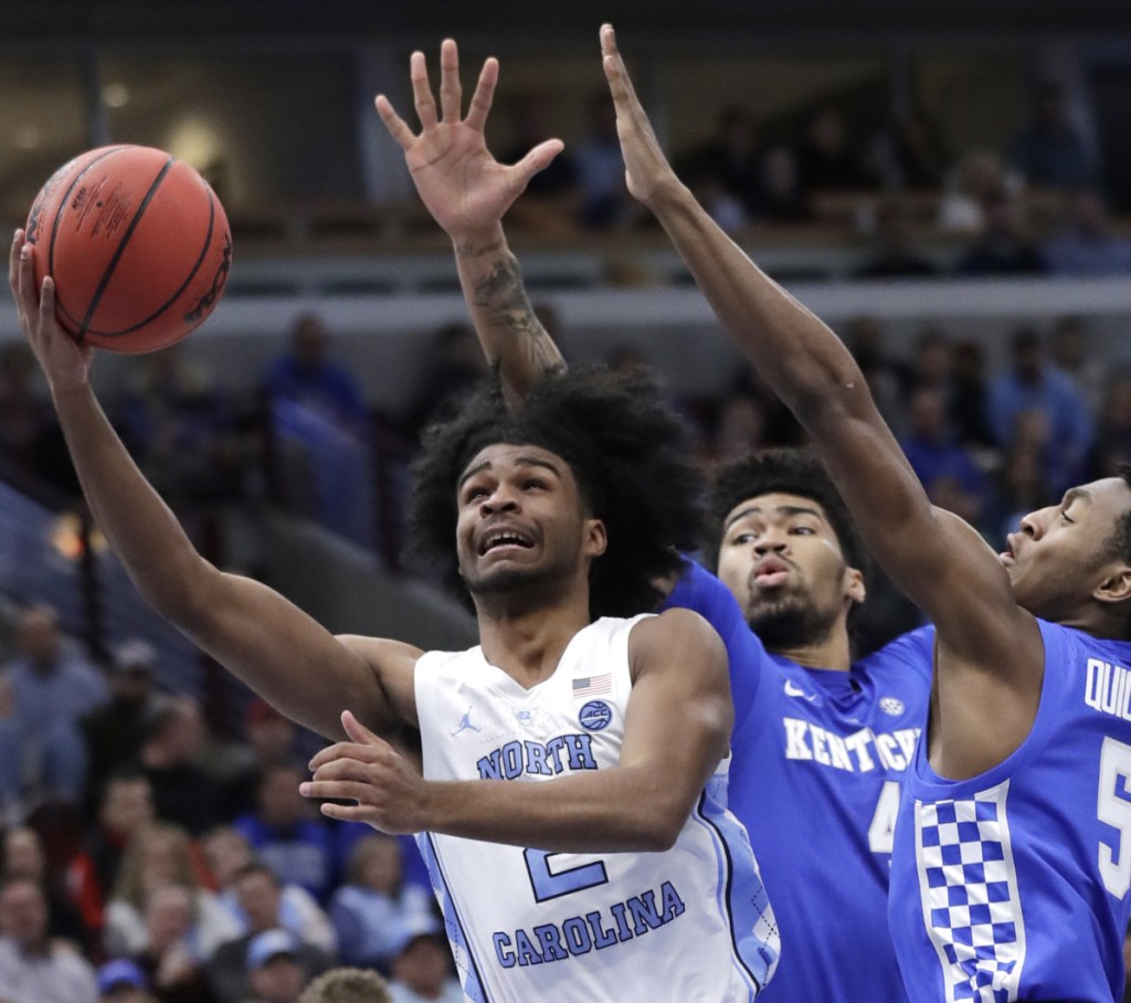 North Carolina guard Coby White, left, takes a shot while being defended by Kentucky forward Nick Richards, center, and guard Immanuel Quickley during the Wildcats' 80-72 victory on Saturday in Chicago.
