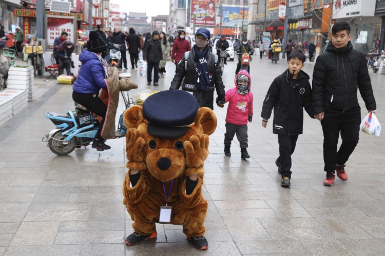 A promoter dressed as a teddy bear rests along a retail street in northern China's Hebei province on Saturday. At least four Chinese cities and one county have restricted Christmas celebrations this year. Churches in another city have been warned to keep minors away from Christmas, and at least 10 schools nationwide have curtailed Christmas on campus, The Associated Press has found.