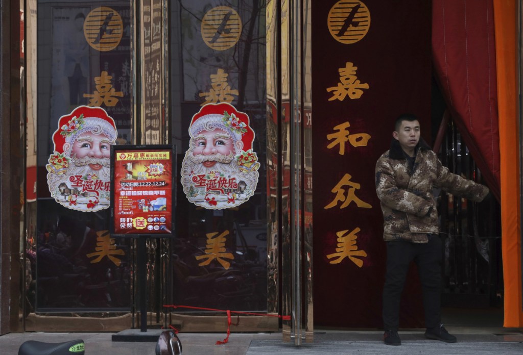 A worker guards the entrance of a shop in Zhangjiakou in northern China's Hebei province on Saturday. The squeeze on Christmas shows how efforts to "normalize" thinking bleed into the everyday lives of many Chinese.