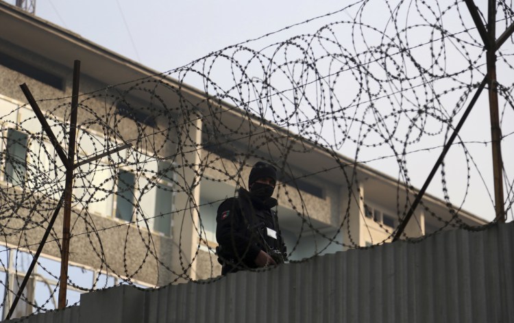 A member of Afghan security forces stands guard after Monday's Christmas Eve attack, in Kabul, Afghanistan. A suicide bomber and gunmen armed with assault rifles and explosives attacked the building in Kabul on Monday, setting off an eight-hour-long siege.