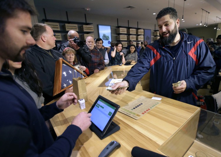 Stephen Mandile, right, of Uxbridge, Mass., is the first to purchase recreational marijuana at the Cultivate dispensary in Leicester, Mass., on Nov. 20, the first day of legal sales in Massachusetts.
