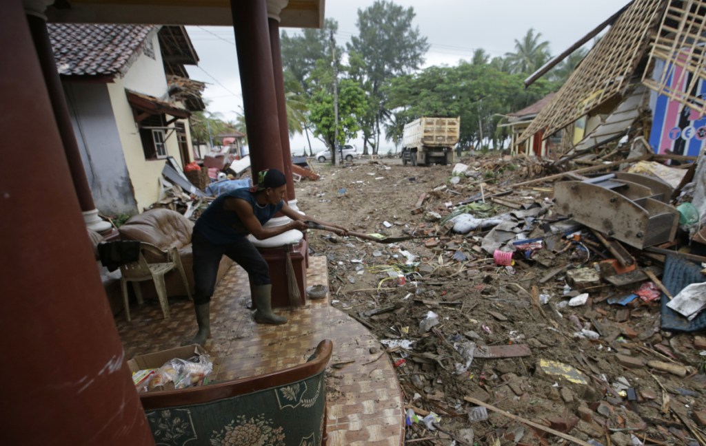 A man cleans the debris from a house at a tsunami-hit area in Carita, Indonesia, Thursday, Dec. 27, 2018. Indonesia has widened the no-go zone around an island volcano that triggered a tsunami on the weekend, killing hundreds of people in Sumatra and Java.