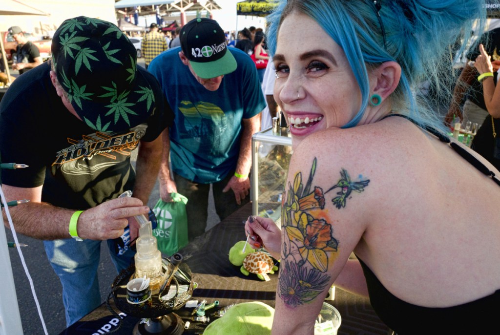 Bud tender Kansas, right, offers customers a puff of cannabis concentrate at the Turtle Puddles' booth at a festival in Adelanto, Calif., in October. Legalization is spreading around the world.