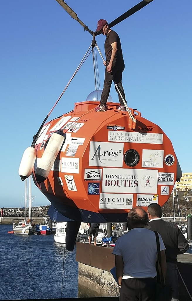 In photograph taken Saturday, 71-year-old Frenchman Jean-Jacques Savin stands on top of his 10-foot-long, 7-foot-wide resin-coated plywood capsule, which will use ocean currents alone to propel him across the sea. Savin set off from El Hierro in Spain's Canary Islands.