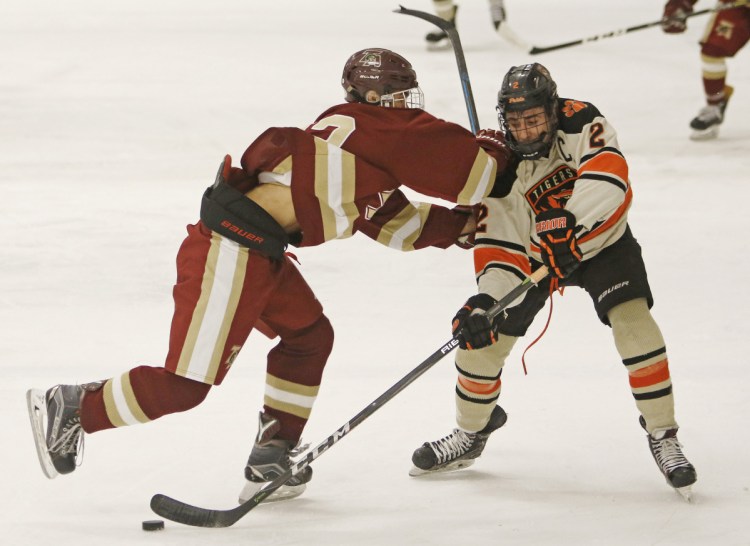 Richard Martin of Thornton Academy, left, attempts to knock Colin Petit of Biddeford off the puck during the second period of Biddeford's 5-4 victory Monday at the Biddeford Ice Arena.
