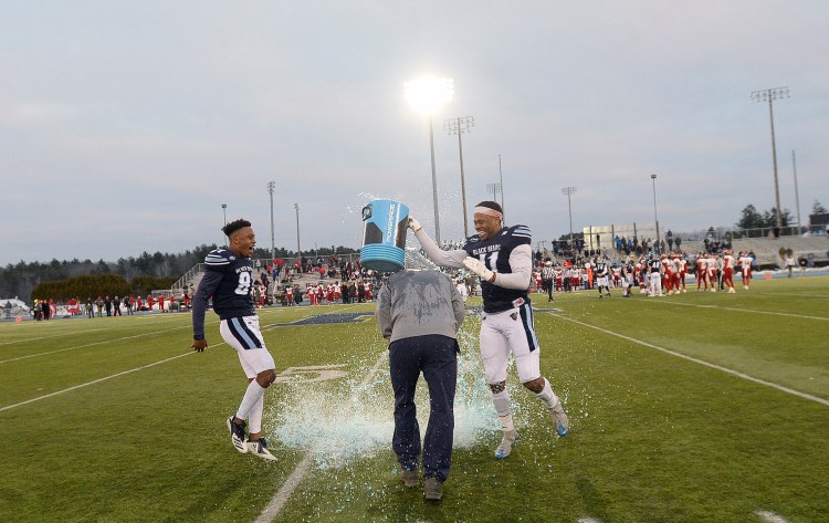 UMaine's Earnest Edwards, left, and Jaquan Blair dump a bucket of icy refreshment over the head of Coach Joe Harasymiak after the clock winds down on the Black Bears' 55-27 win over Jacksonville State in the second round of the FCS playoffs on Saturday in Orono.