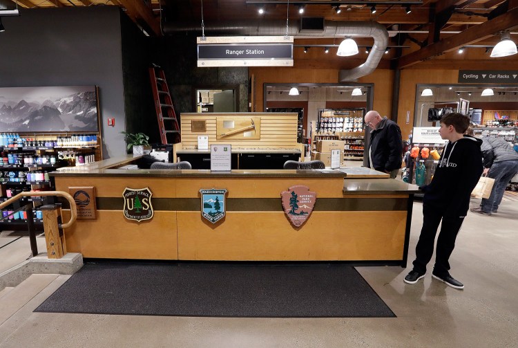 REI Co-op customers in the company's Seattle store stand near a ranger station kiosk that was closed Wednesday because of the federal government shutdown. The desk is normally staffed by rangers who provide information and passes for public lands in Washington state.