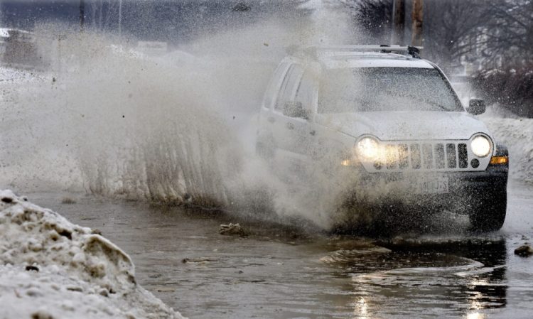 A vehicle blasts water from a huge puddle that developed on Oak Street in Waterville as rain and warm weather combined to make Thursday wet and messy.