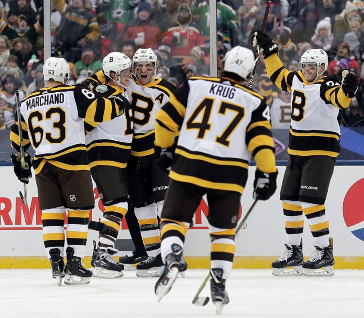 Bruins center Patrice Bergeron, center, celebrates with teammates after scoring a goal in the second period of the Bruins' 4-2 win over the Chicago Blackhawks in the NHL Winter Classic Tuesday at Notre Dame Stadium in South Bend, Ind.