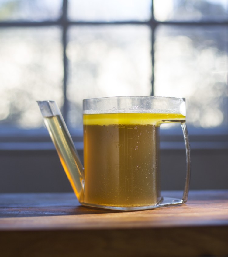 Yellow fat sits atop stock in a fat separator. Top: Chicken and egg drop soup, made with the stock.