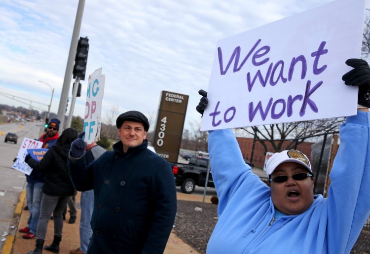 Emma James, right, and co-worker Vincent Cuenca protest the government shutdown outside the Federal Center on Friday in St. Louis. James is a processor in the multifamily housing division. Cuenta processes payments to FEMA contractors.