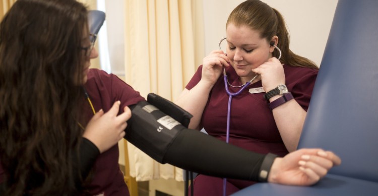 Nursing student Rachel Souza, right, practices checking blood pressure at Saint Joseph's College. Health care is a sector where there are expected to be good jobs for at least the next decade.