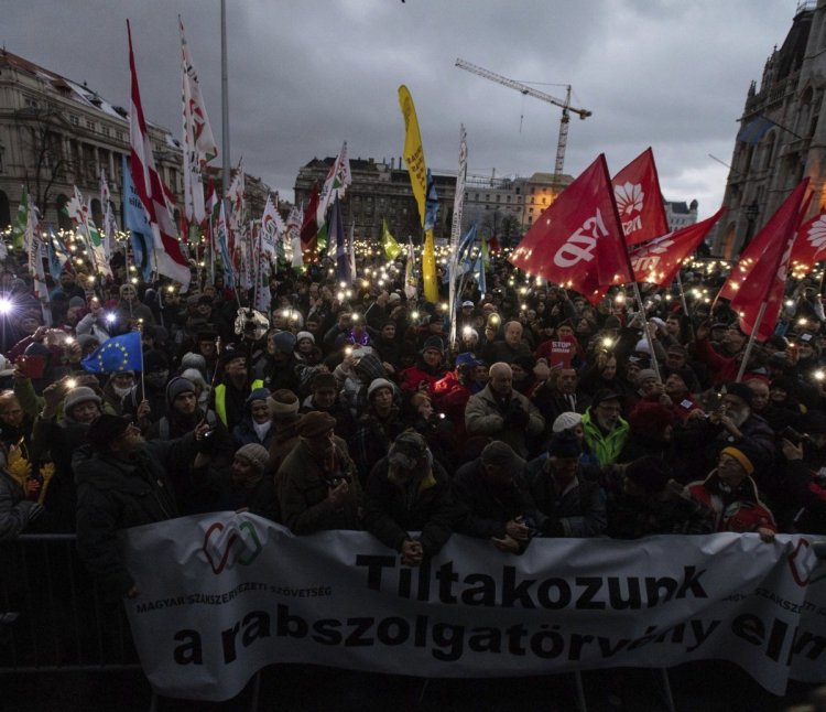 Anti-government demonstrators carry a banner reading "We protest against the slave bill" as they protest in front of the Parliament building at Kossuth Square in Budapest, Hungary, on Saturday.