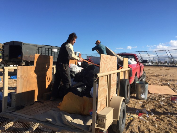 Volunteers Travis Puglisi and Shawn Snyder load a trailer of trash in Joshua Tree National Park on Dec. 31.