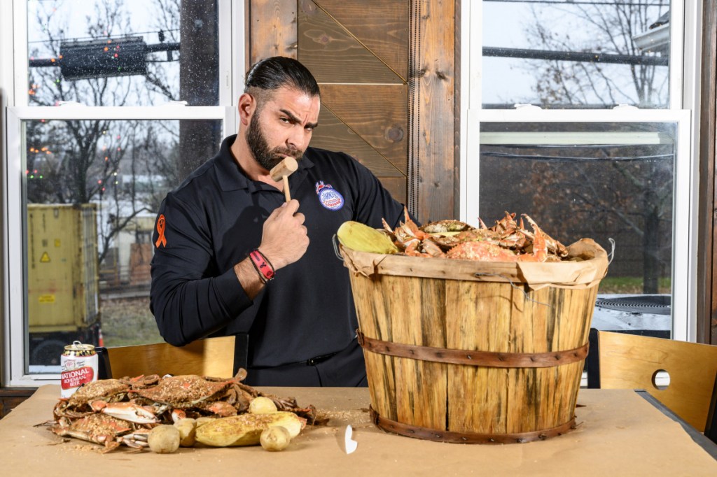 John Minadakis, owner of Jimmy's Famous Seafood, with a bushel of steamed crabs. PETA targeted Baltimore, putting up a billboard against eating seafood. He responded with his own billboard.