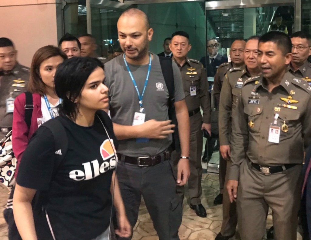 Saudi resident Rahaf Mohammed Alqunun walks past an immigration official and others Monday before leaving the Suvarnabhumi Airport in Bangkok. She had been placed in a hotel there and told she would be put on a Monday morning flight to Kuwait, but her pleas online from the room prevented that.
