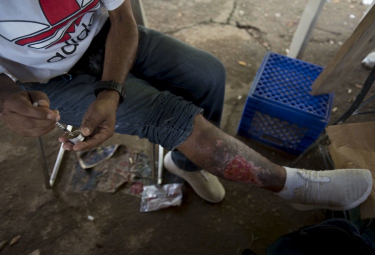 A man fills his syringe with heroin in an area popular with users behind an abandoned home in Humacao, Puerto Rico. The user, who did not want to give his name, said an infection on his leg developed as a result of repeatedly injecting cocaine. He said he uses cocaine to balance out the effect of heroin.