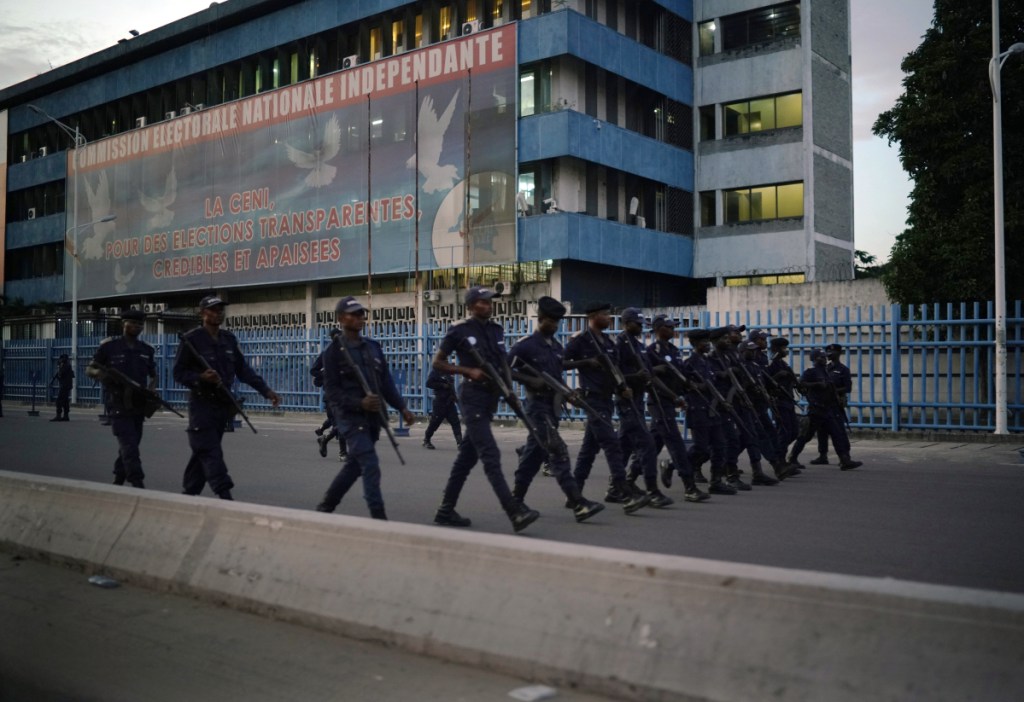 Congolese riot police patrol Thursday outside the independent electoral commission building at dusk in Kinshasa. Few election protests were reported.