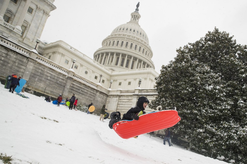 Two children go over a ramp as they sled on Capitol Hill as a winter storm arrives in the region, Sunday in Washington. Associated Press /Alex Brandon