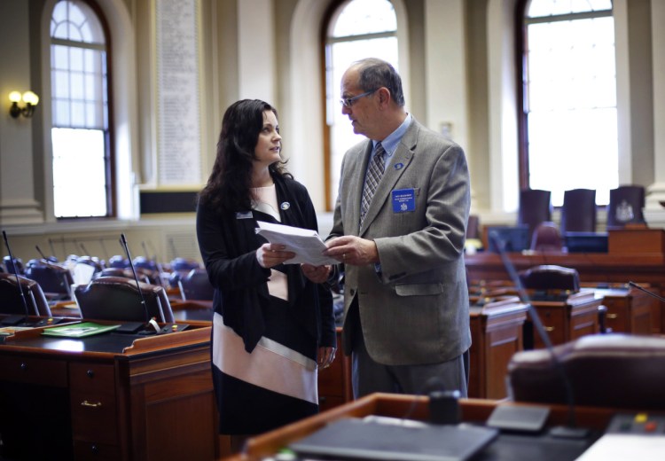 Republican state Reps. Amy Arata and her father, Richard Bradstreet, discuss legislation Thursday in the House chamber at the State House in Augusta. State records compiled by Maine's legislative library suggest they're the first father and daughter to serve as legislators together in Maine history. But they're not the first pair nationwide.