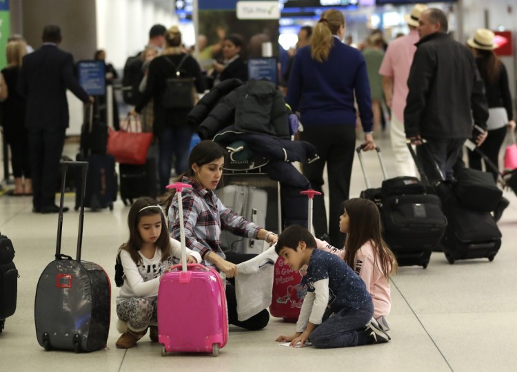 Travelers organize their luggage before entering a security checkpoint at Miami International Airport on Friday. The three-day holiday weekend – one with inclement weather in the forecast –is likely to test the nation's air-travel system as the partial government shutdown enters its fifth week.