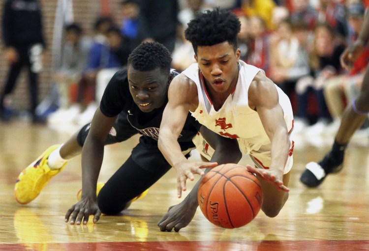 Loki Anda of Deering, left, and Tyree Bitjoka of South Portland scramble for a loose ball Friday night during Deering's 50-41 victory at Beal Gym. Deering beat the Red Riots for the second time this season.