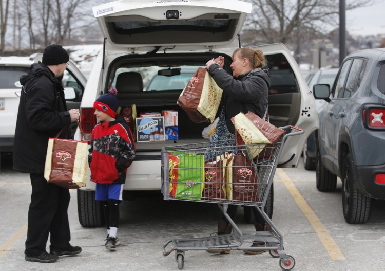 Damien Pierce, 7, waits as his parents, Loree and Nick, load groceries at the Hannaford supermarket in Portland on Saturday. The family was stocking up for the Patriots game.