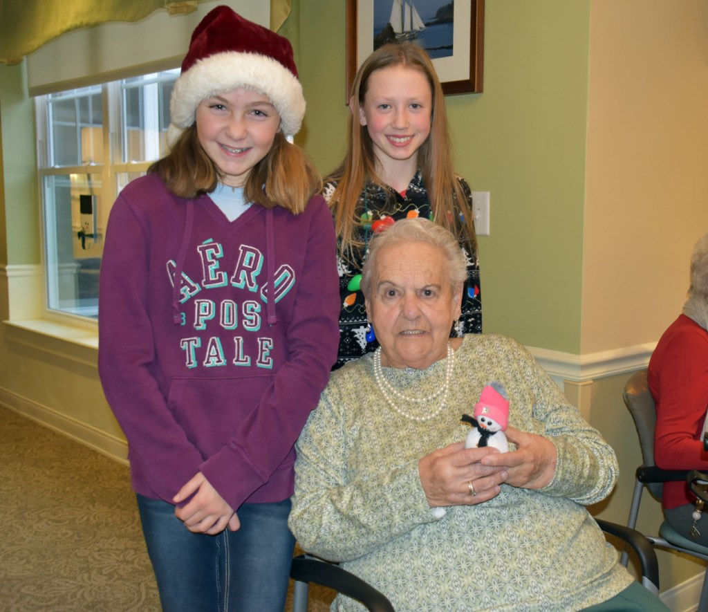 Avita resident Rose Fawcett receives a homemade snowman from Wells Junior High School students Teagan Hludik, left, and Molly Tavares.