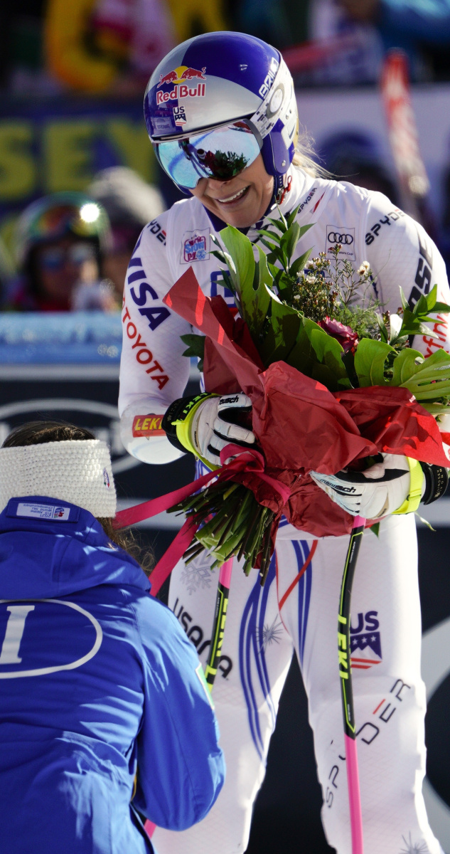 Lindsey Vonn, top, receives flowers from friend and rival Sofia Goggia of Italy after Sunday's World Cup super-G race in Cortina D'Ampezzo, Italy.