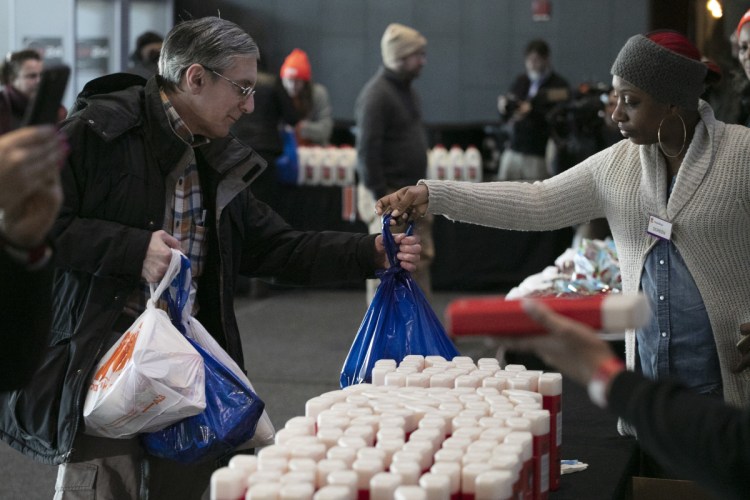 A government worker, left, gets groceries at a food bank for government workers affected by the shutdown, on Tuesday, the 32nd day of the shutdown, in the Brooklyn borough of New York.