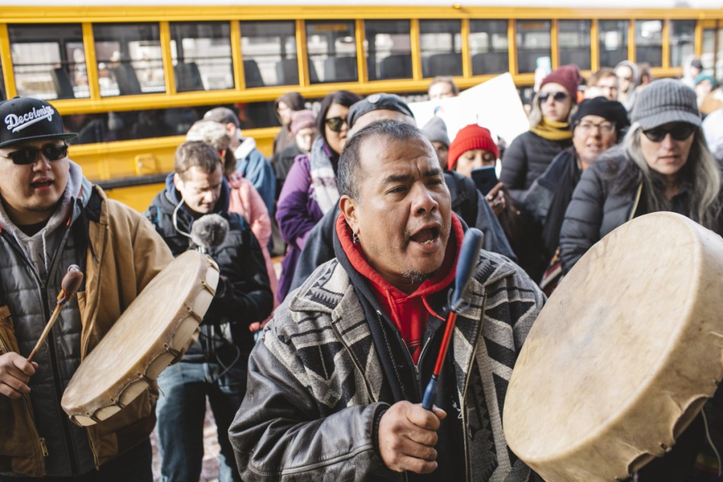 Sleepy Eye LaFromboise, left, beats a drum outside the Covington Catholic Diocese on Tuesday, while a member of a motorcycle club that backs President Trump talks with Native Americans in support of the students.
