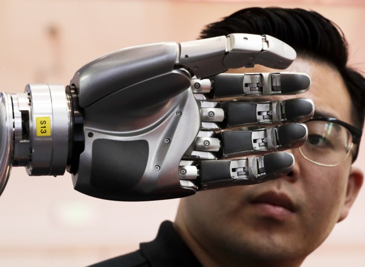 A visitor inspects a robotic hand at the World Robot Conference in Beijing in 2017. A Brookings Institution study suggests workplace automation will continue to displace U.S. workers.