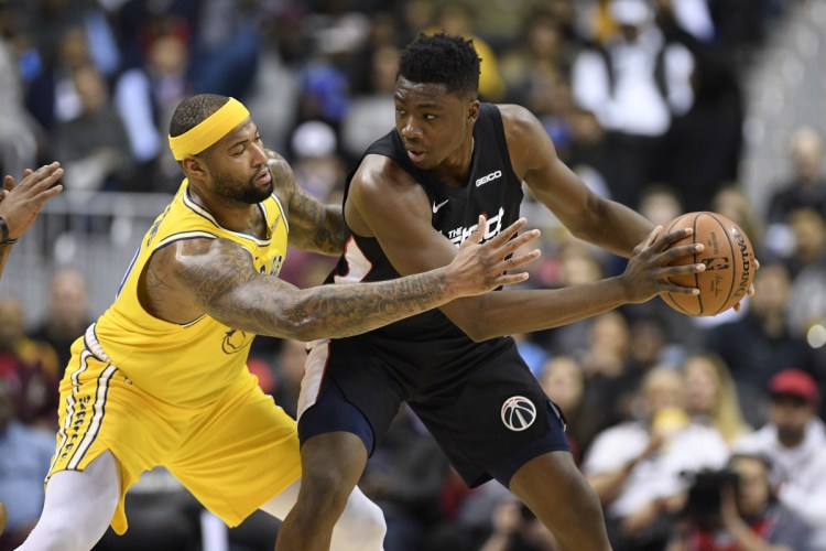 Golden State's DeMarcus Cousins reaches for the ball against Washington center Thomas Bryant in the first half of Thursday's game at Washington.