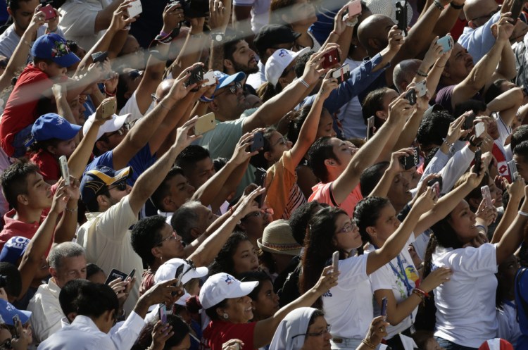 People hold out their phones as Pope Francis arrives in his popemobile to celebrate Mass in the Santa Maria la Antigua cathedral in the old section of Panama City on Saturday. Francis turned his attention to the country's priests and religious sisters as he reacheed the midway point in his five-day Central American visit.
