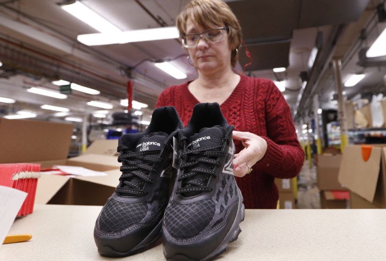 Ruby Williams inspects a pair of sneakers designed for the military at the New Balance factory in Norridgewock.