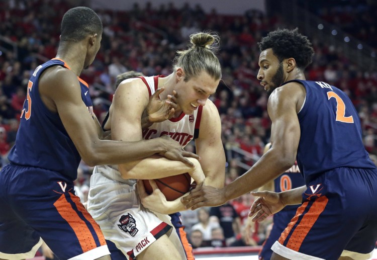 Virginia's Mamadi Diakite, left, and Braxton Key pressure North Carolina State's Wyatt Walker in the first half Tuesday night at Raleigh, N.C. Virginia won in overtime, 66-65.