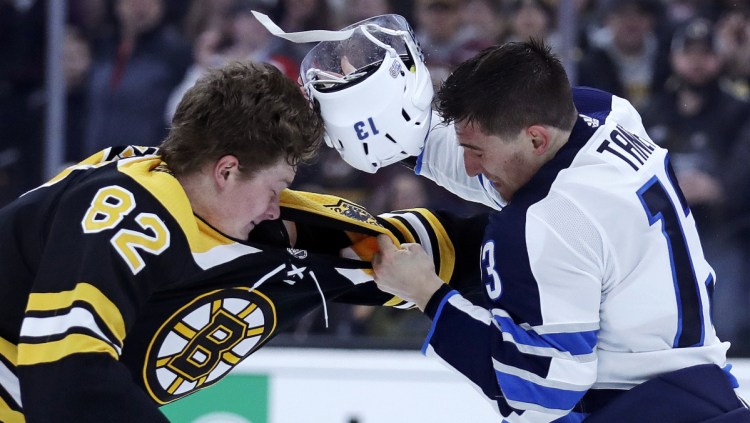 Winnipeg Jets left wing Brandon Tanev, right, loses his helmet in a fight with Boston Bruins center Trent Frederic during the second period of the Bruins' 4-3 shootout loss Tuesday night in Boston.