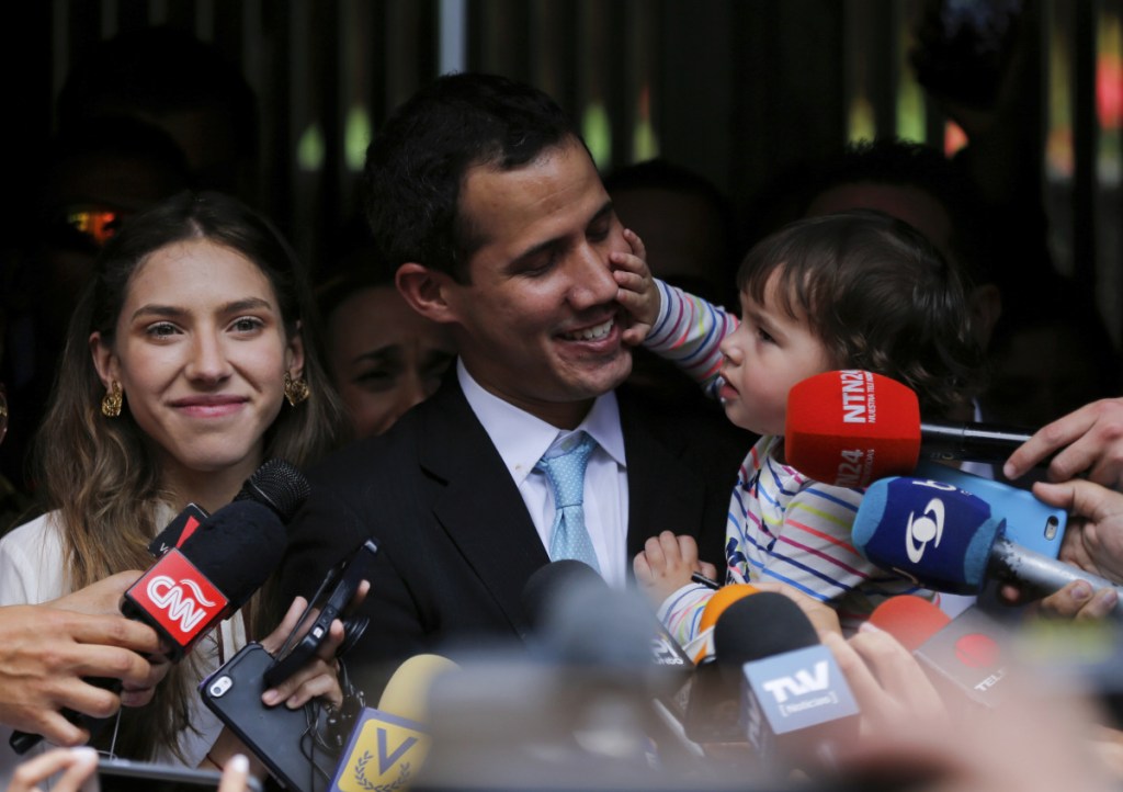 Opposition National Assembly President Juan Guaido, accompanied by his wife, Fabiana Rosales, smiles at his 20-month-old daughter, Miranda, during a news conference outside their apartment, in Caracas, Venezuela, Thursday. Guaido said security forces showed up at their home in an attempt to intimidate him. (AP Photo/Fernando Llano)