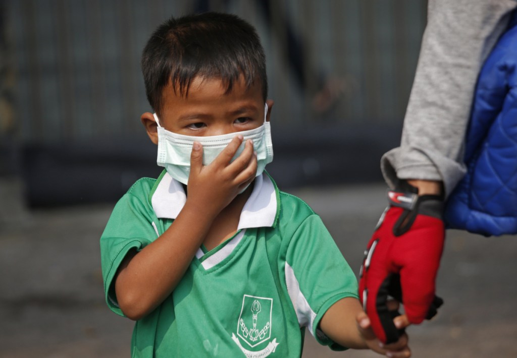 A young boy wears a protective mask for the high levels of air pollution as he's picked up from school in Bangkok, Thailand, on Wednesday