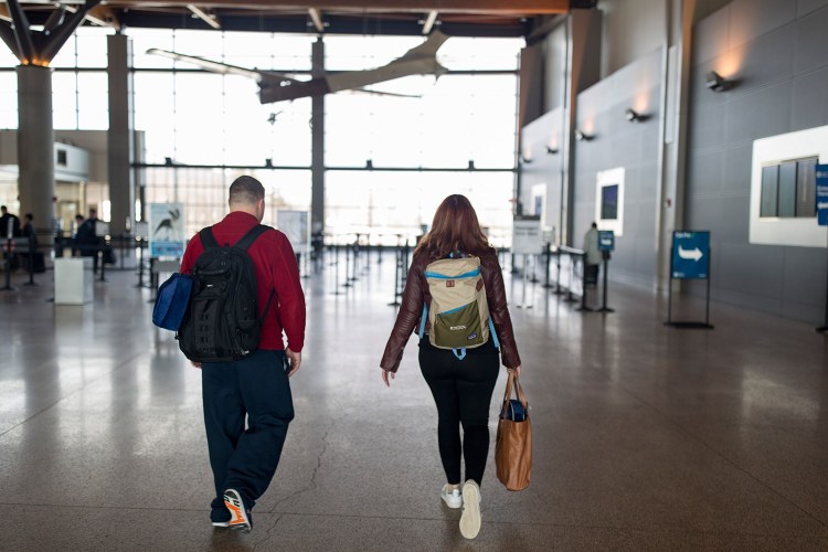 Kyle Benson, of Westbrook, left, and Mo Placey, of Gorham, walk to the security check for their flight to Phoenix at the Portland International Jetport on Friday. Placey and Benson said they hadn't heard any news about delays on their flights. "Fingers crossed," Placey said. 