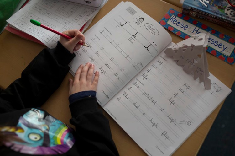 Reese Hennessey practices cursive words with the letter "i" in them in Tracy Burns' class at Narragansett Elementary School in Gorham in December.