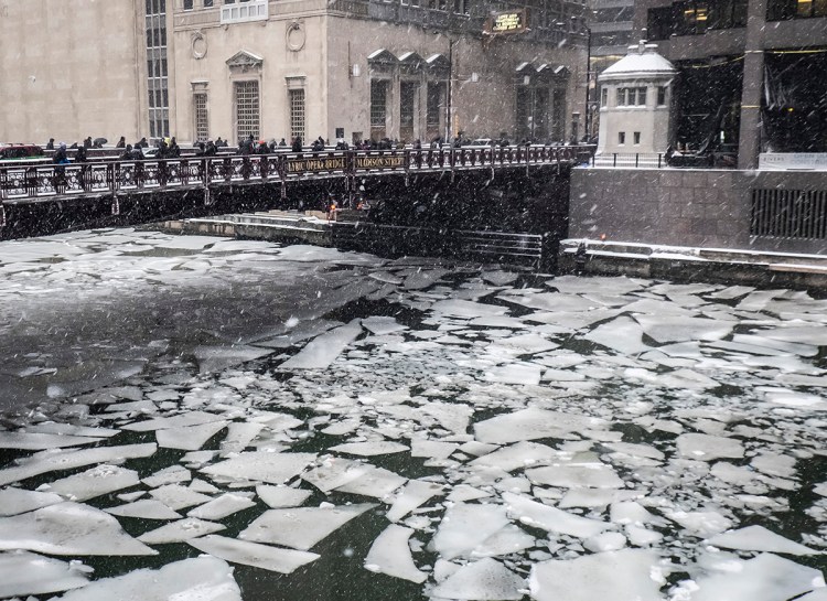 Pedestrians cross an icy Chicago River on Madison St. near the Civic Opera House in Chicago, Monday, Jan. 28, 2019. 