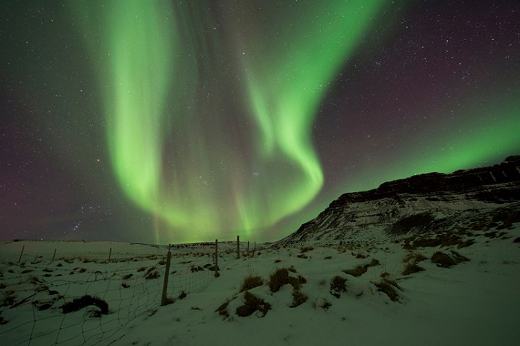 An aurora borealis over  Iceland in 2017. The phenomenon is caused when accelerated electrons from the upper atmosphere follow Earth's magnetic field to polar regions where they collide  oxygen and nitrogen atoms. The magnetic North Pole is moving westward by about 30 miles a year.