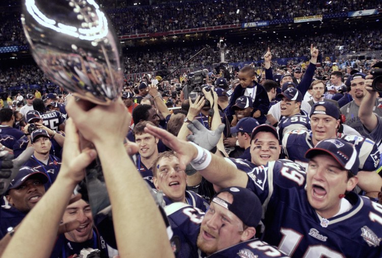 Lemme touch it: New England Patriots players reach out for the Vince Lombardi Trophy after their dramatic 20-17 victory over the St. Louis Rams in Super Bowl XXXVI in New Orleans on Feb. 3, 2002.